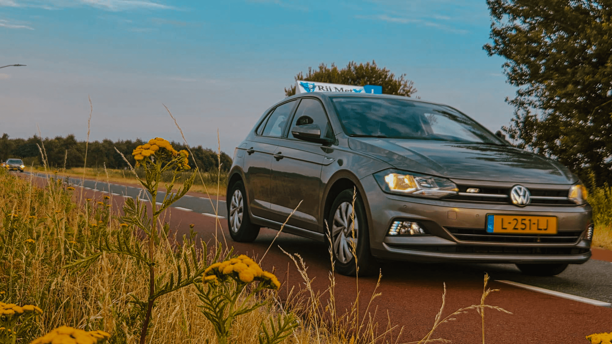 Lesauto van Rij MetX met dakbord langs een landweg
